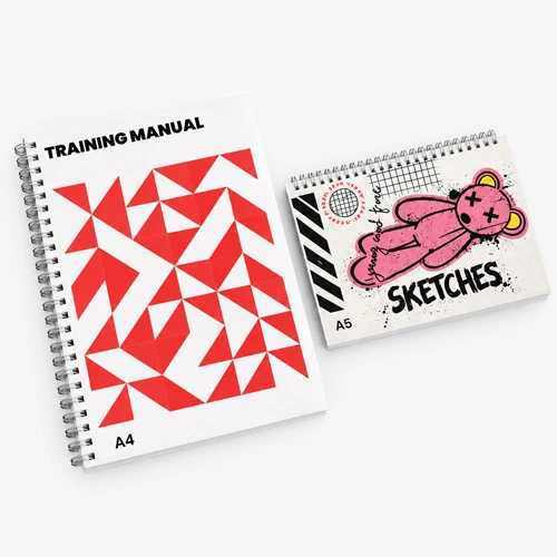 Two spiral-bound notebooks labeled "Training Manual" (A4) and "Sketches" (A5) on a white surface.