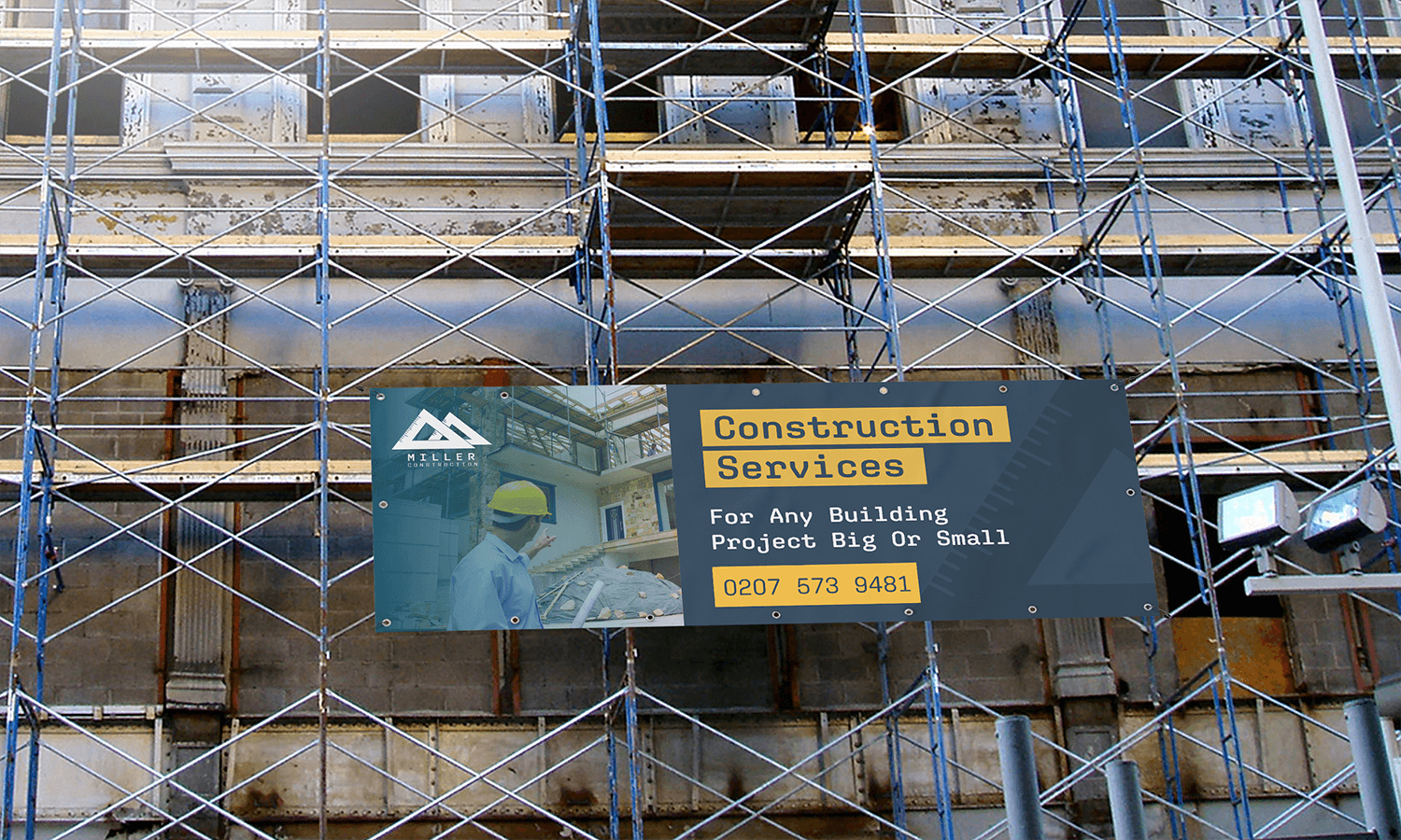 Scaffolding surrounds a building with an outdoor banner advertising construction services in front.