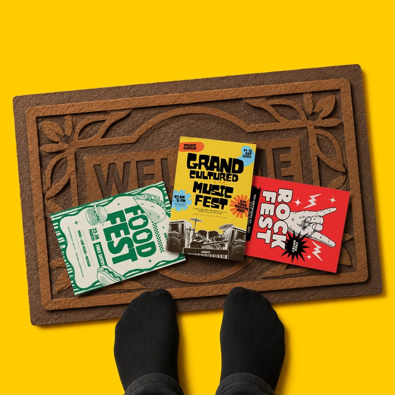 A person in black socks stands by a doormat with three colorful festival flyers on it.