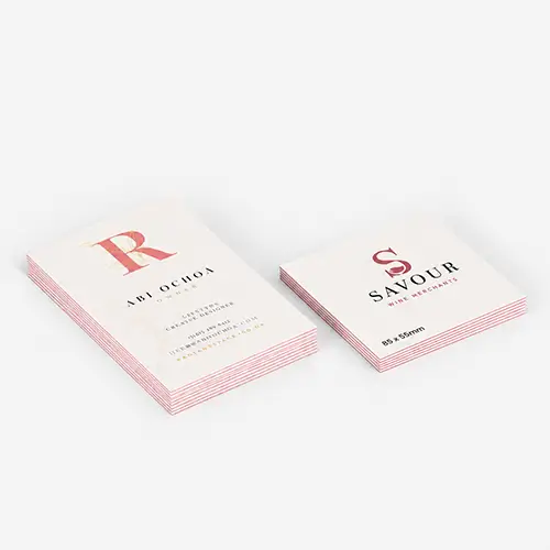 Two stacks of luxe coloured business cards displayed on a light surface, showing different designs and text.