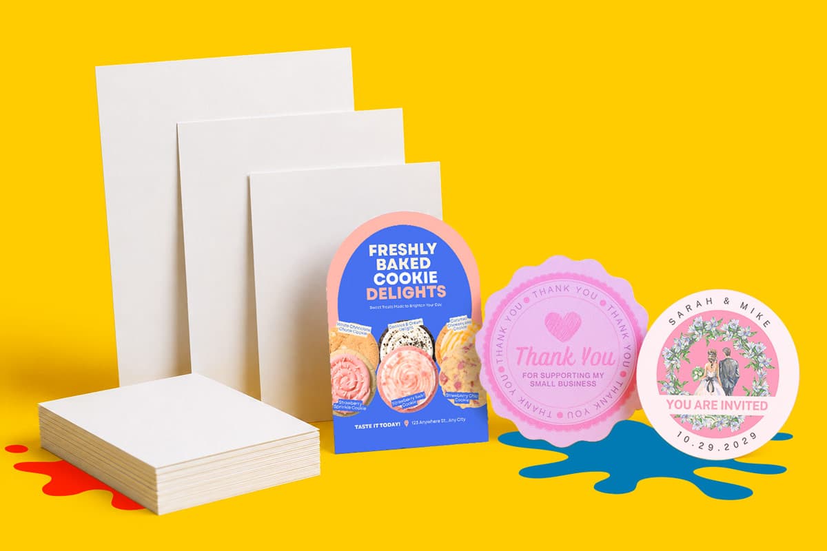 Assorted white paper flyers and colourful custom shapes invitations arranged on a yellow background.