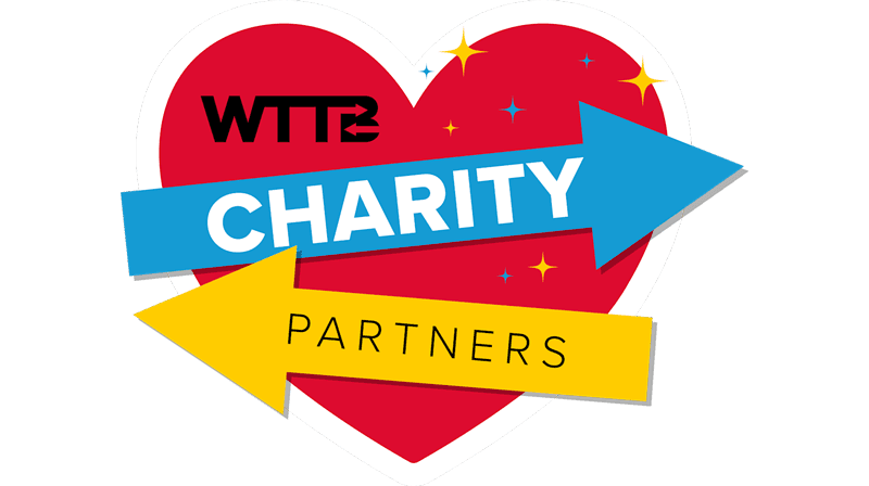 Red heart with "WTTB CHARITY PARTNERS" written on blue and yellow arrows across it.