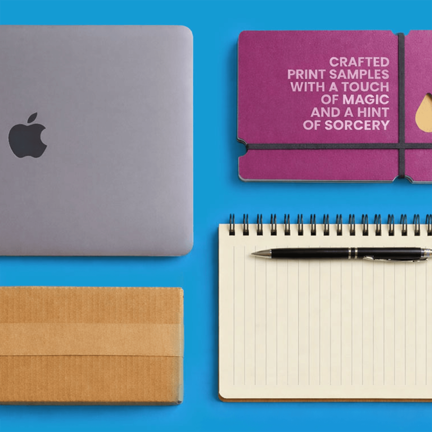 Laptop, notebook with pen, cardboard box, and purple card on a blue surface.