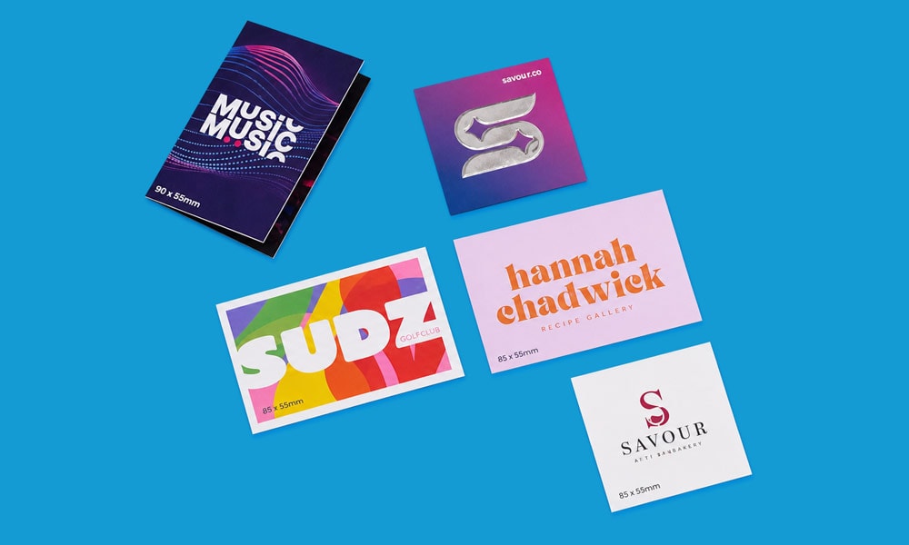 Five colourful business cards with various designs arranged on a wide, blue background.