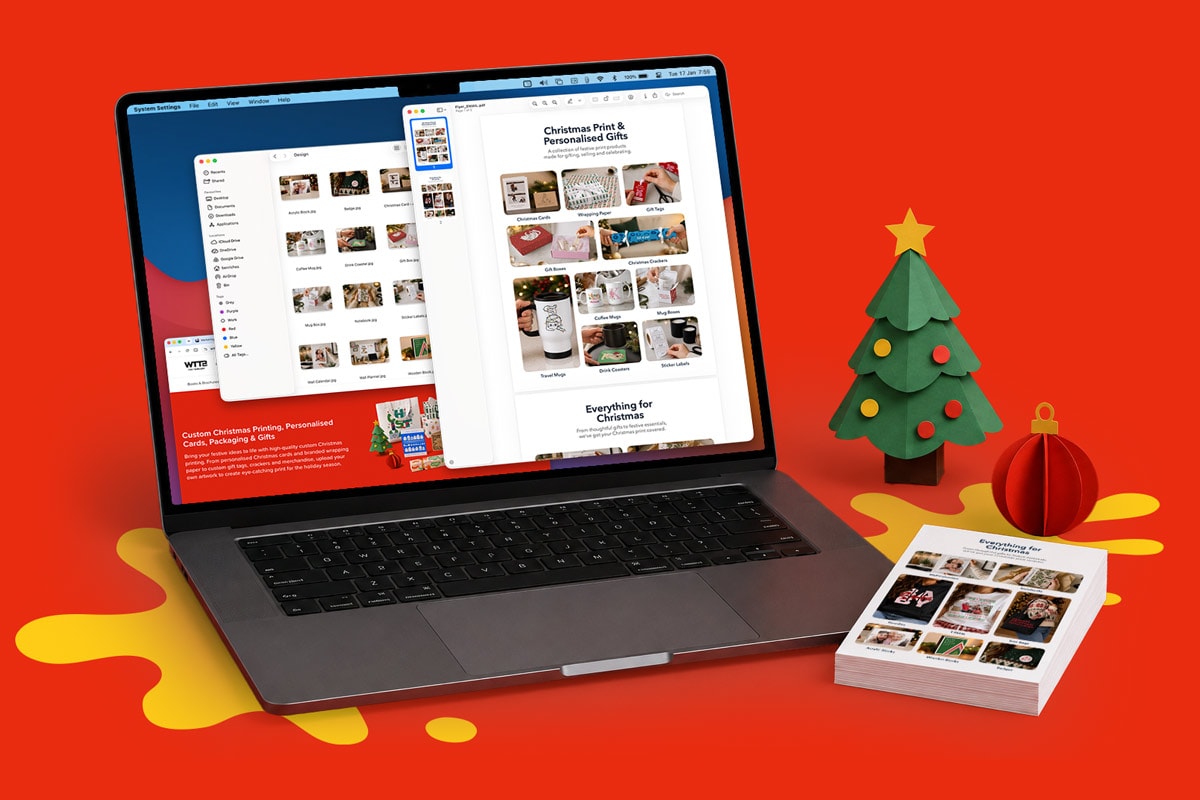 Laptop displaying photo gift website, with holiday decorations and printed photo cards beside it.