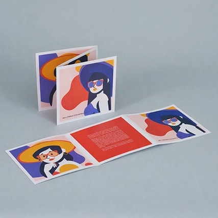 Folded brochure with colorful illustrations of people wearing sunglasses and hats on a gray surface.