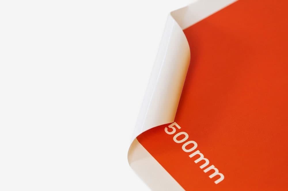 A corner of an orange sheet curled up, showing "500mm" printed near the edge.
