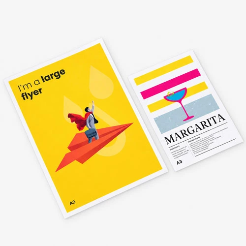 Two A3 posters on a gray surface; one yellow with a paper plane, one colourful with a cocktail.