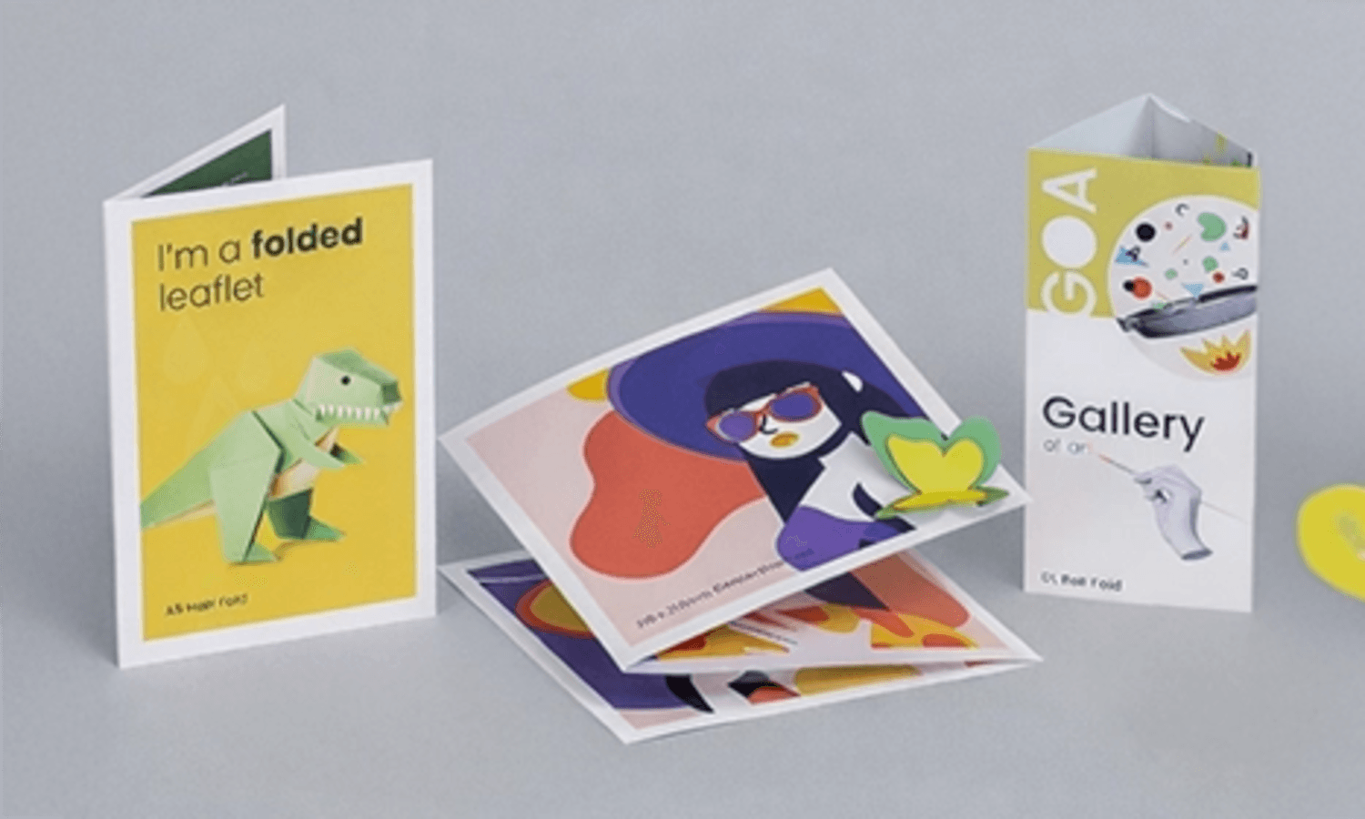 Four colourful folded cards and postcards with various illustrations on a wide, light grey background.