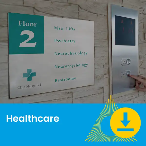 Wall sign for hospital’s second floor listing departments; hand pressing elevator button nearby.