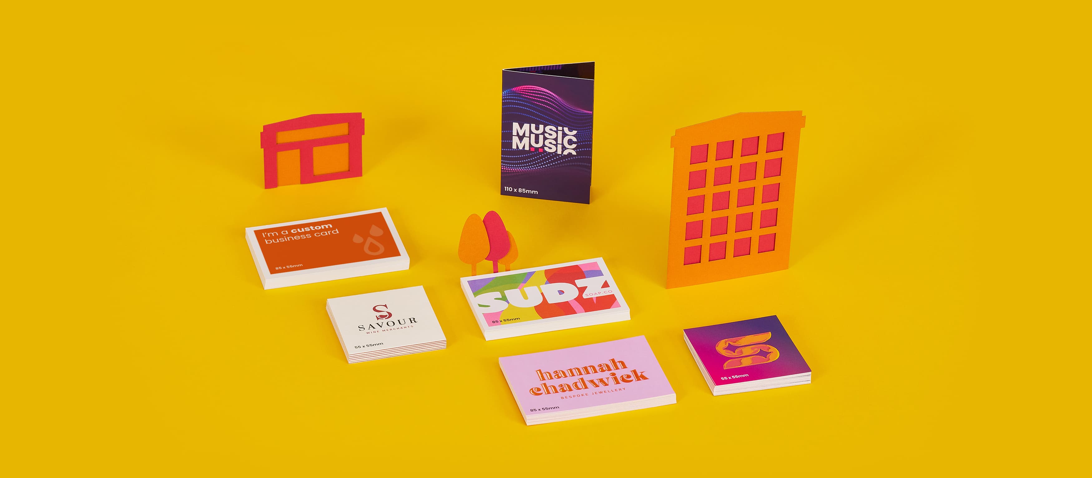 Various colorful business cards displayed with abstract cityscape models on a yellow background.