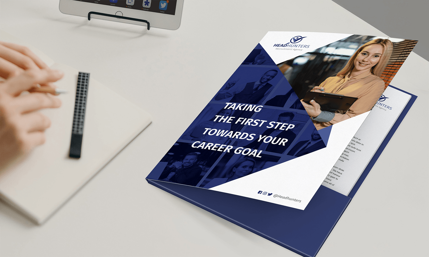 Person writing in notebook near a presentation folder titled "TAKING THE FIRST STEP TOWARDS YOUR CAREER GOAL".