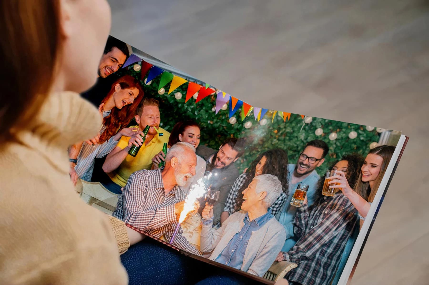 Person looks at a photo album page of a festive outdoor group gathering.