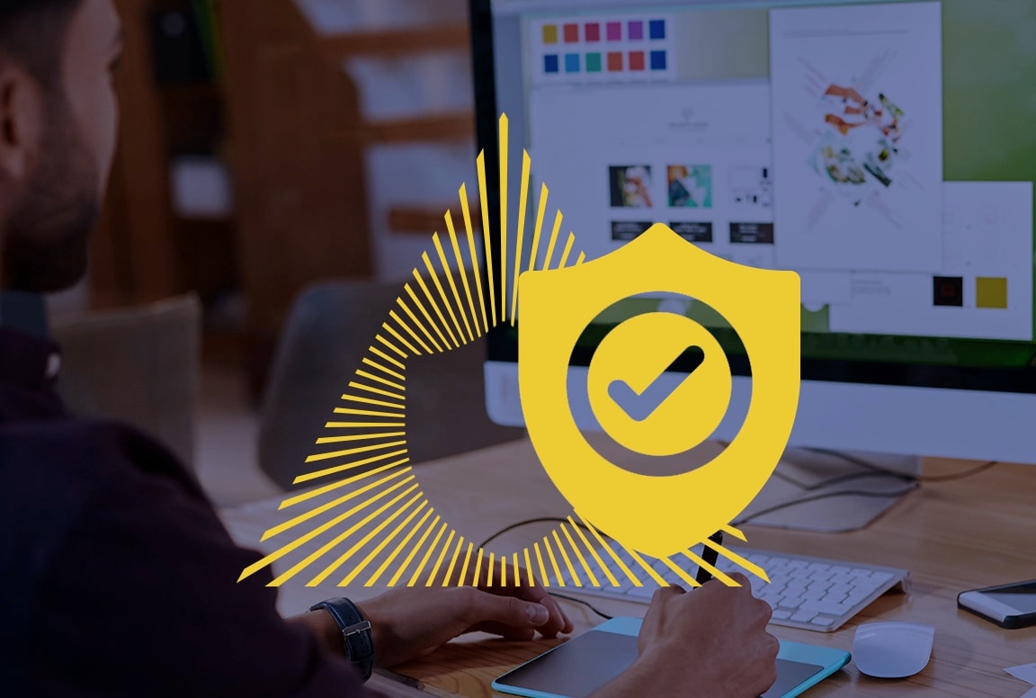 Person using a graphic tablet at a computer, with a digital security shield icon overlay.