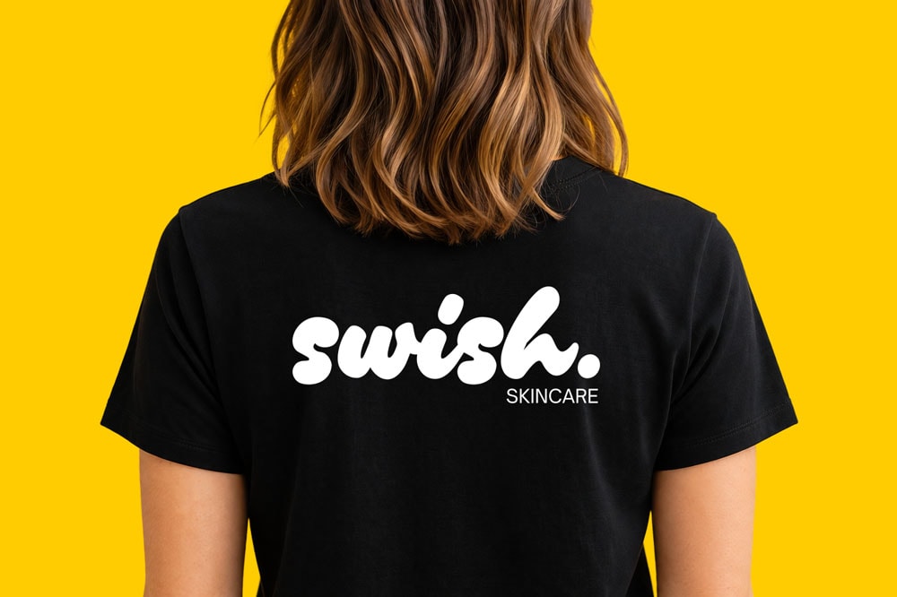 Person wearing a black t-shirt with "swish. SKINCARE" logo on the back, against yellow background.