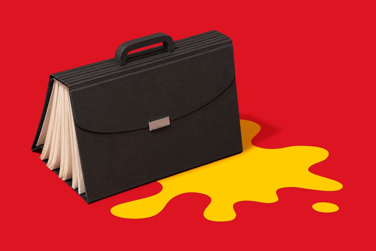 Black briefcase with papers sits on red surface with a yellow spill-shaped area underneath.