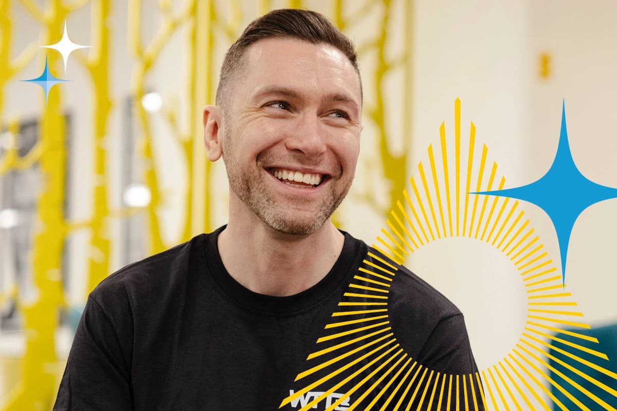 Man smiling indoors, wearing a black T-shirt, with yellow and blue graphic shapes over the image.