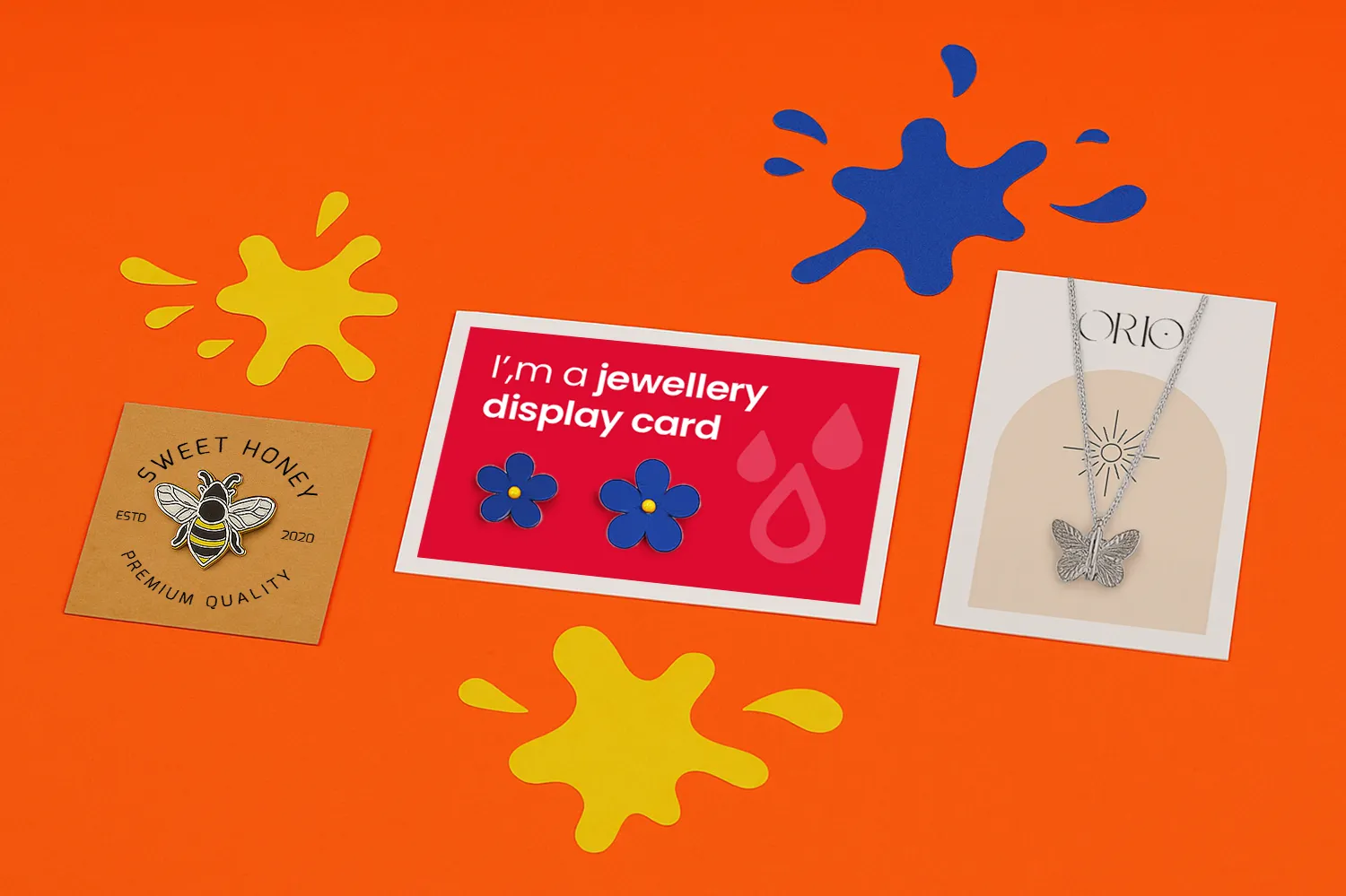 Three product display cards are arranged on an orange surface with yellow and blue splatters.