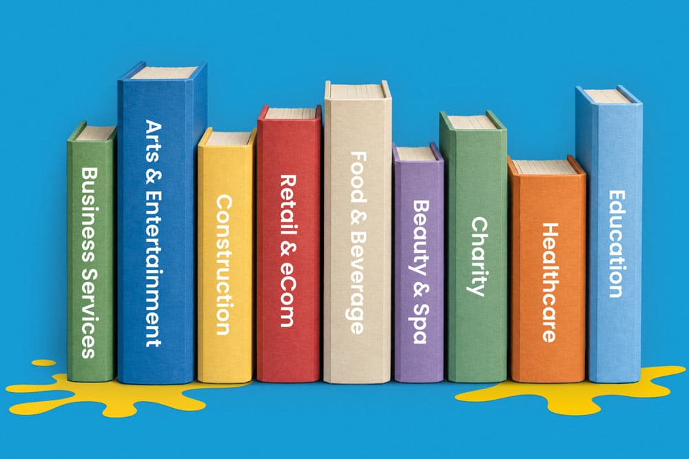Nine upright books labeled with different industry sectors on a blue background with yellow paint.