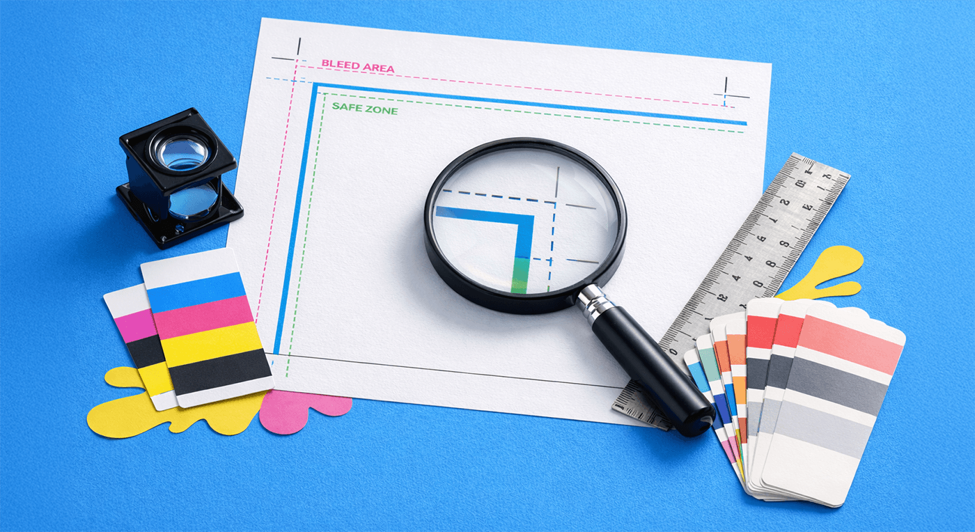Magnifying glass on print proof with color swatches, ruler, and loupe on a blue background.