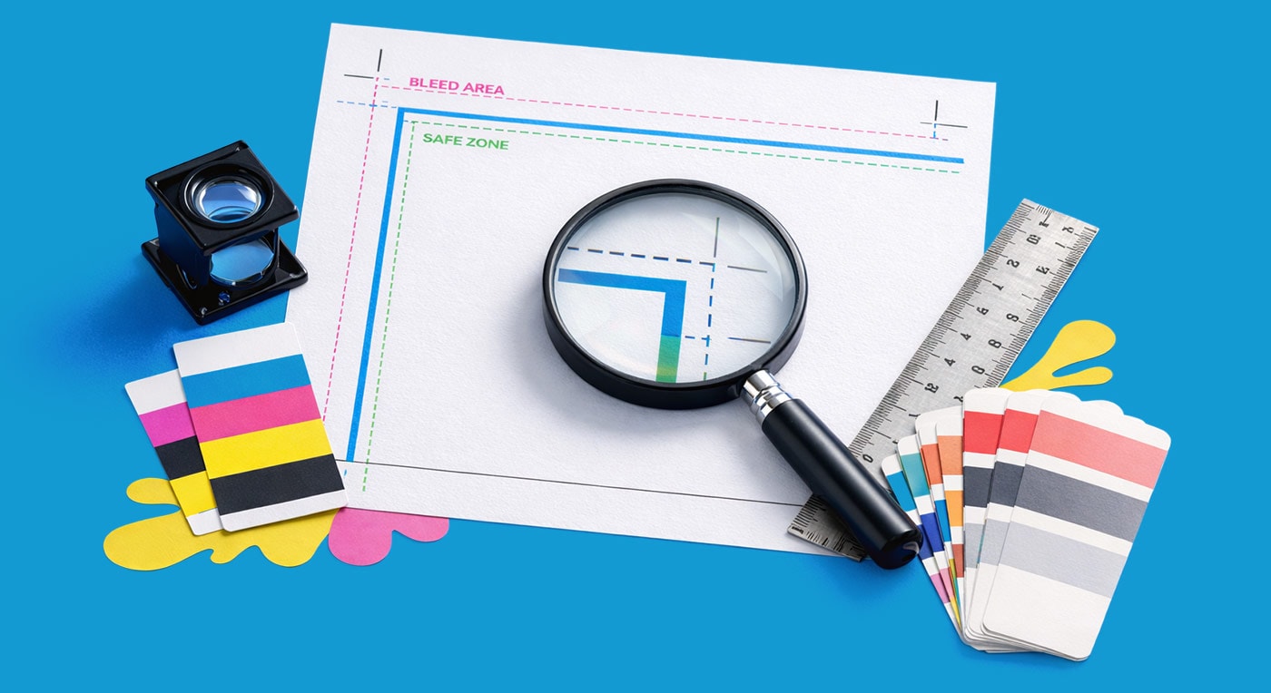 Magnifying glass on print proof with color swatches, ruler, and loupe on a blue background.