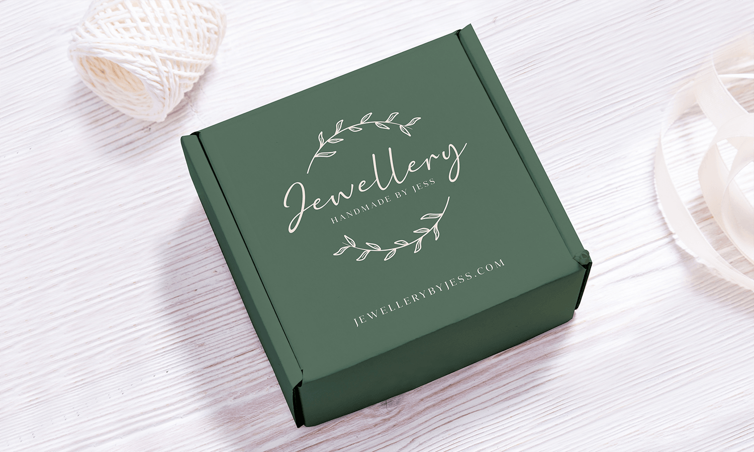 Green eCommerce gift box with "Jewellery by Jess" branding, placed on a light wooden surface.