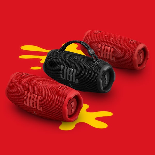 Three JBL portable speakers, two red and one black, displayed on a red background with a yellow splash.