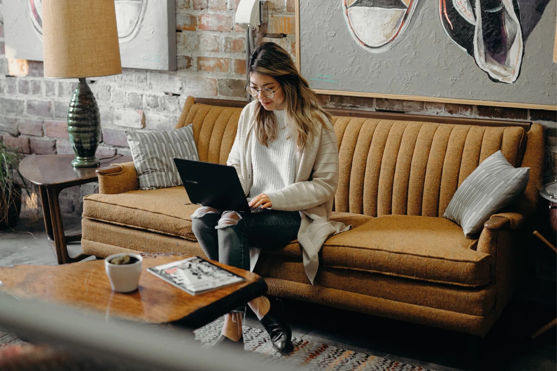 A woman comfortably sitting on a couch, engaged with her laptop