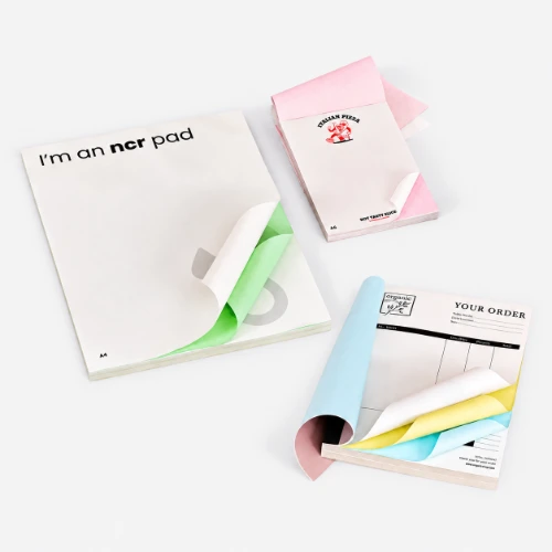 Three NCR pads with colored carbonless pages shown partially open on a white background.