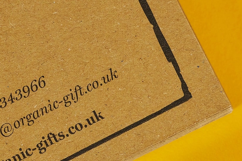 Close-up of brown paper with contact details printed in black ink on a yellow background.