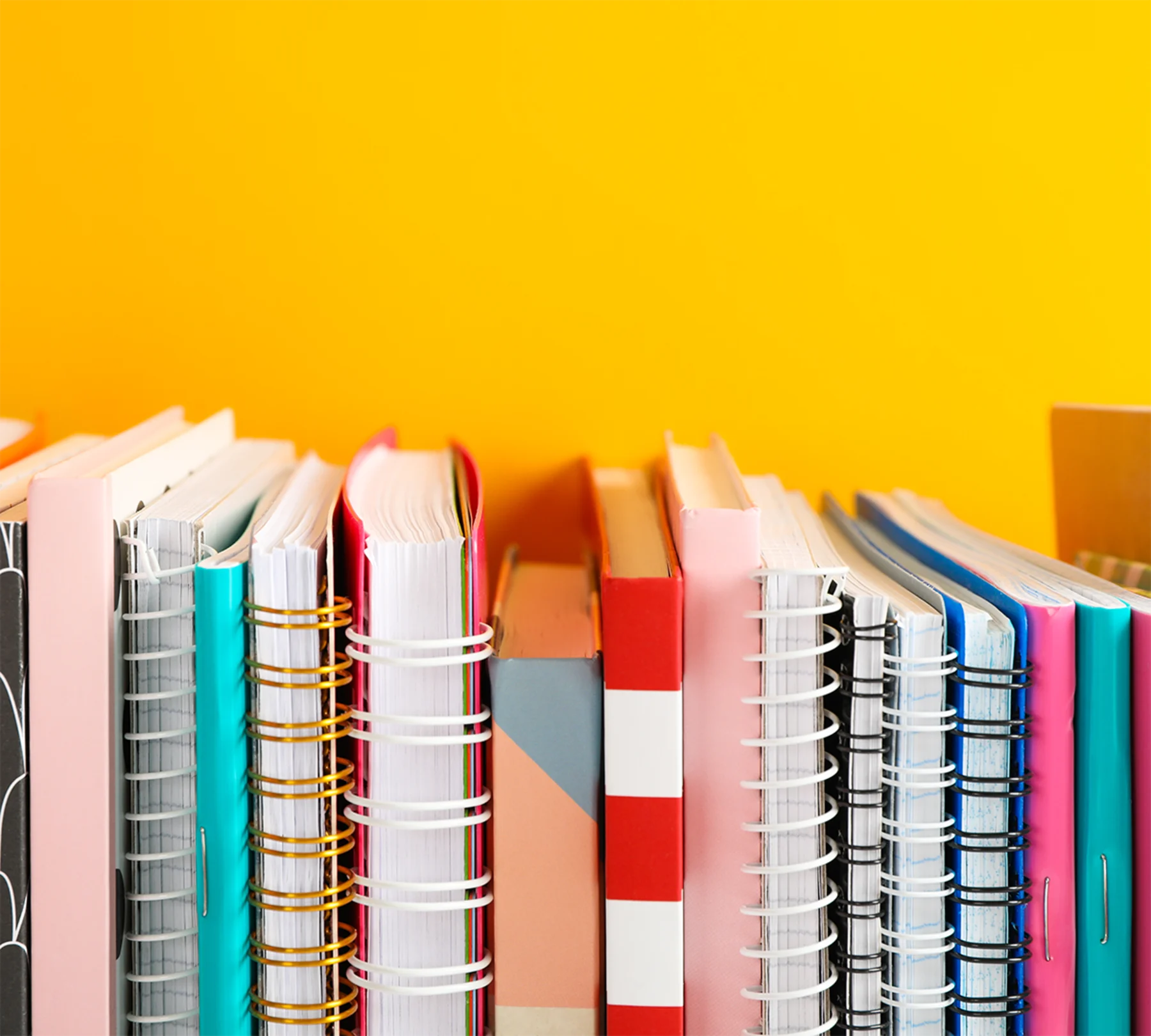A stack of colourful books arranged neatly on a vibrant yellow background