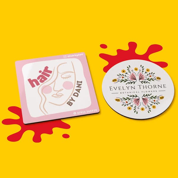 Two custom business stickers on a yellow background with red paint splatters behind them.