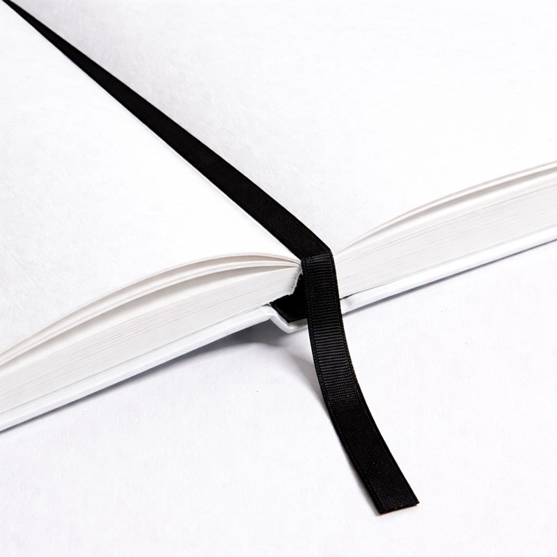 Open blank notebook with a black ribbon bookmark lying across the pages.