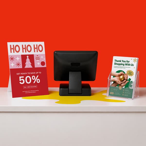 Retail counter with a monitor, holiday sale sign, and customer thank-you flyer on display.