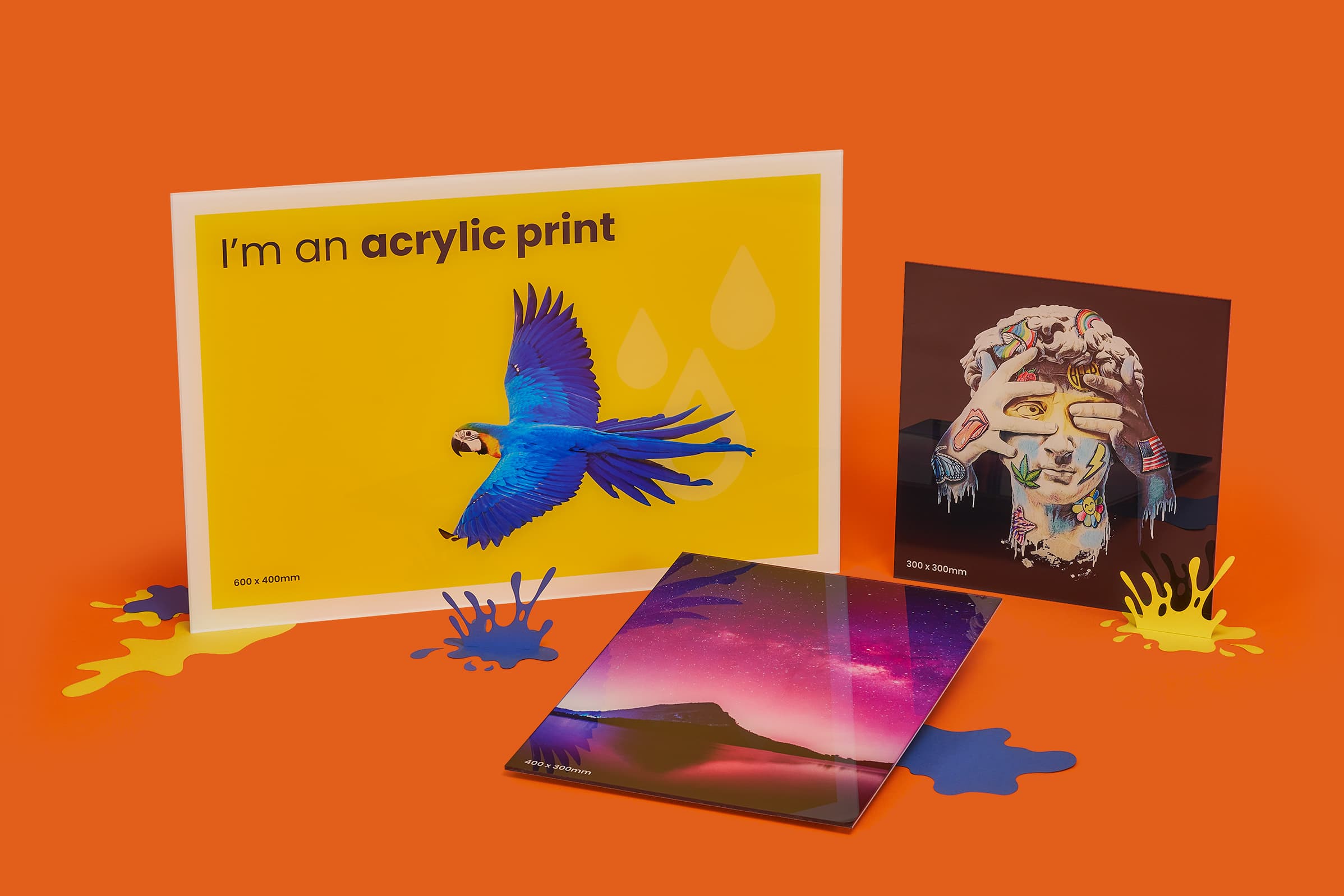 Three colorful acrylic prints displayed on an orange background.