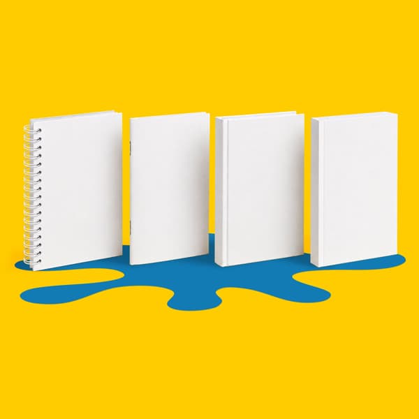 Four blank notebooks stand upright on a yellow background with a blue splatter shape underneath.