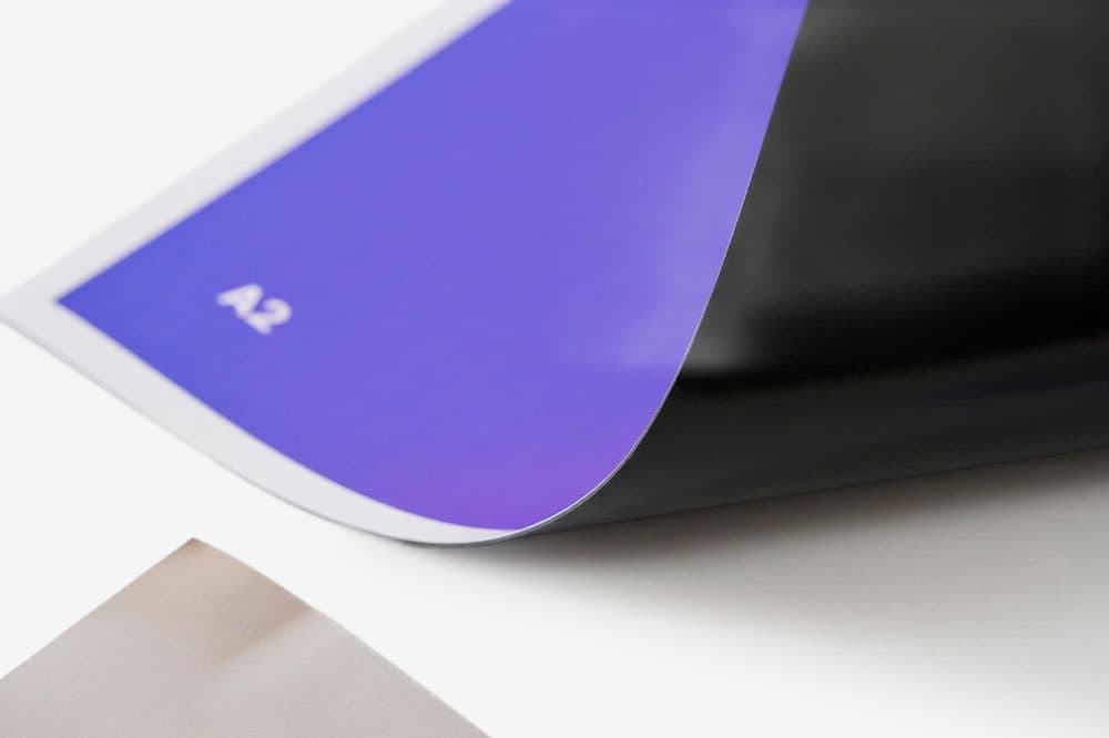 A close-up of a curled A2 size purple and black sheet on a white surface.