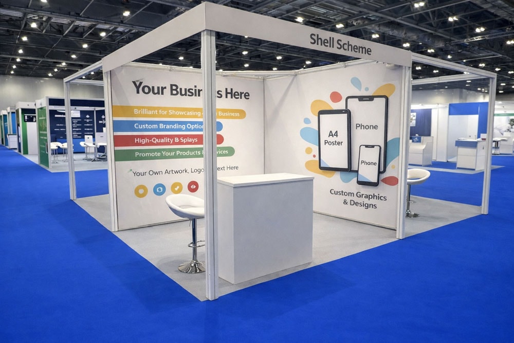 Exhibition booth with promotional posters, counter, and seating in a convention center.