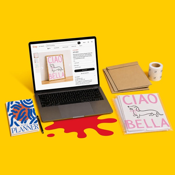 Laptop with Etsy shop open, beside planner, pen, mailing supplies, and a “Ciao Bella” print.