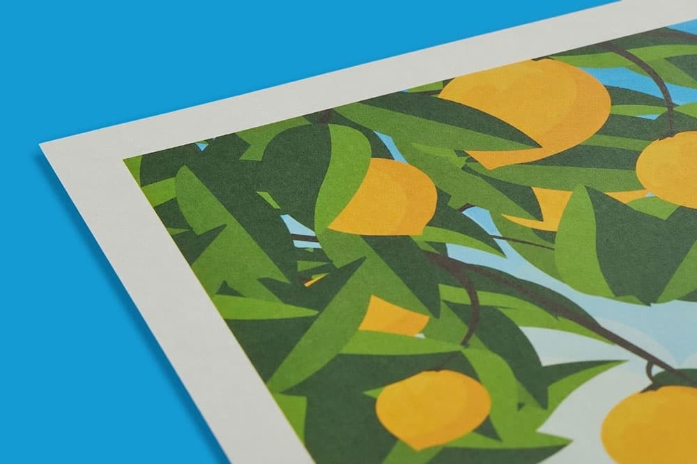 Close-up of an art print featuring oranges and green leaves against a blue background.
