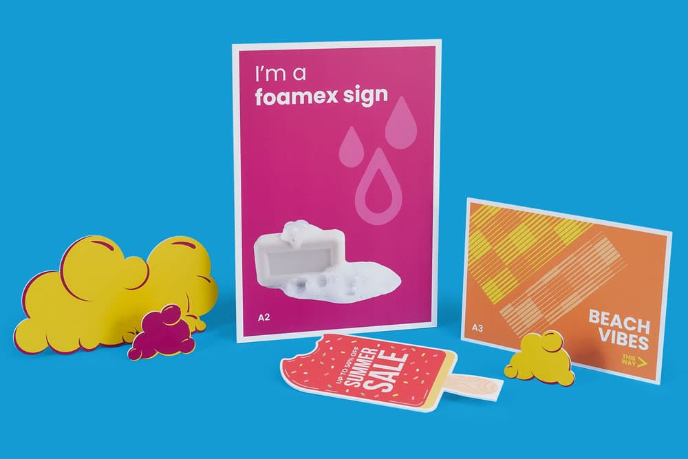 Colorful display of printed foam signs, including sale and beach themes, against a blue background.
