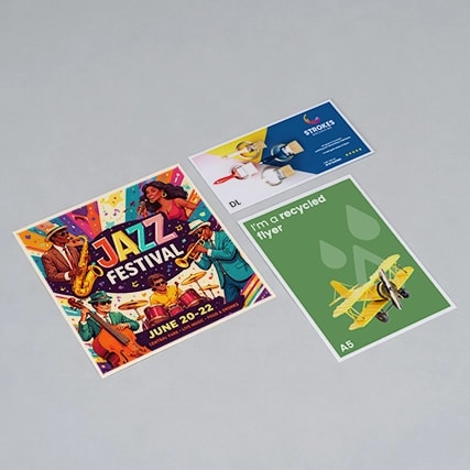 Three different printed flyers are laid out on a plain light gray surface.