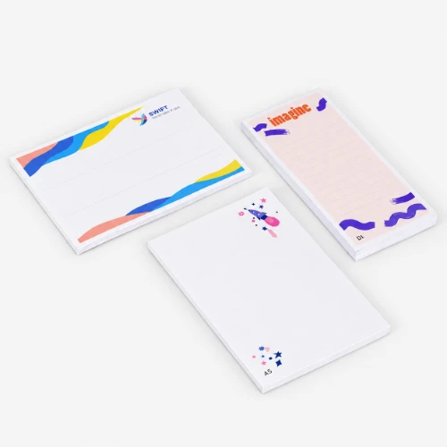 Three decorated notepads with different designs and lined or blank pages on a plain background.
