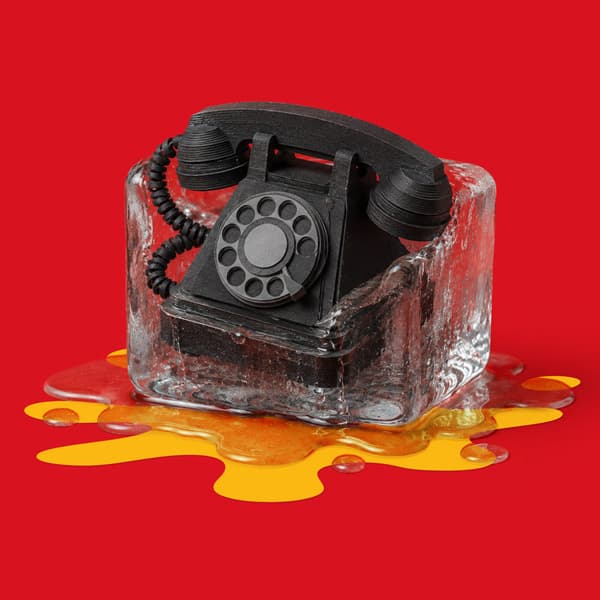 A black rotary phone is encased in melting ice against a solid red background.