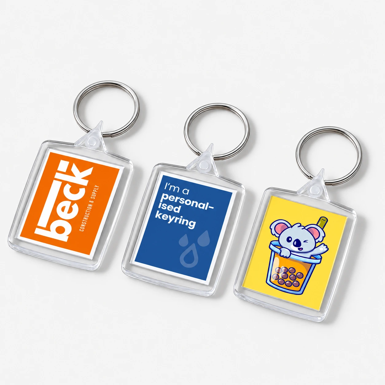 Three square keyrings featuring a company logo, text, and a cartoon koala in a boba tea cup.