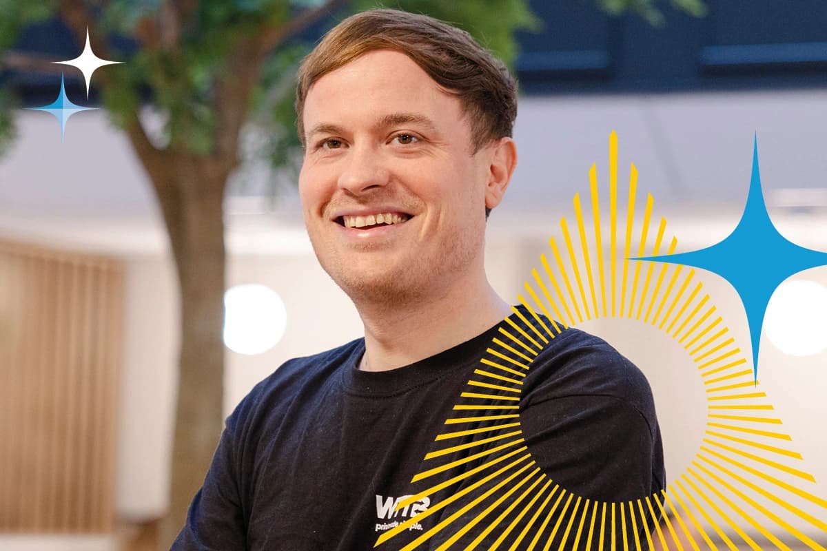 Smiling person in a black t-shirt stands indoors with graphic elements overlaid on the image.