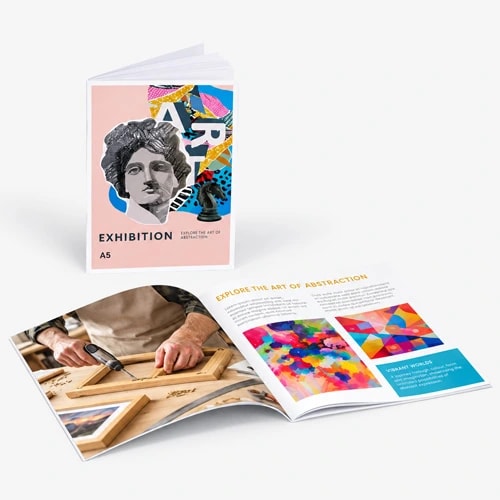 Two art exhibition booklets, one closed and one open, displayed on a light gray surface.