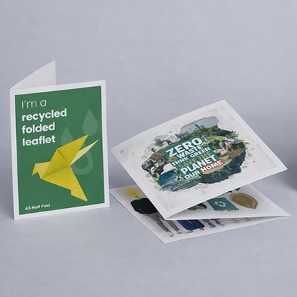 Three folded leaflets with eco-friendly designs displayed on a gray surface.