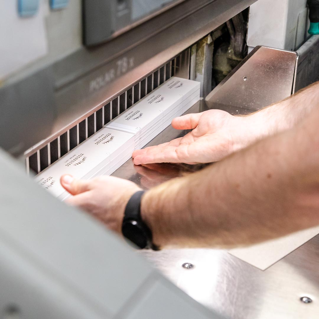 A man skillfully uses a paper-cutting machine in a professional setting