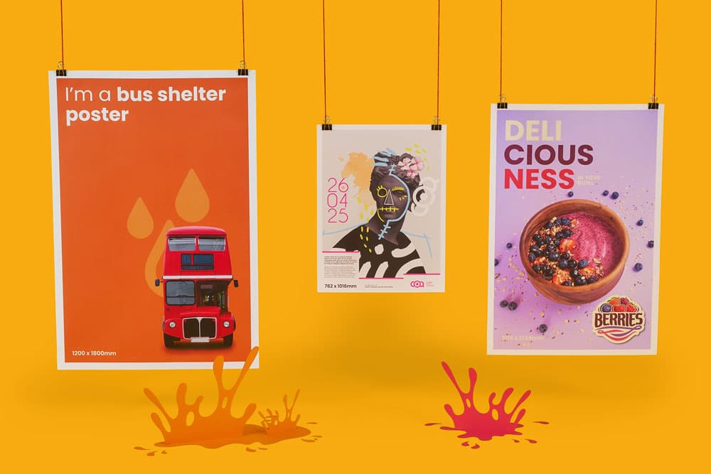 Three colourful posters are hanging against an orange background with paint splatters below.